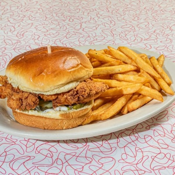 Big Boy's crispy chicken sandwich with pickles and mayonnaise, served with a side of golden fries.