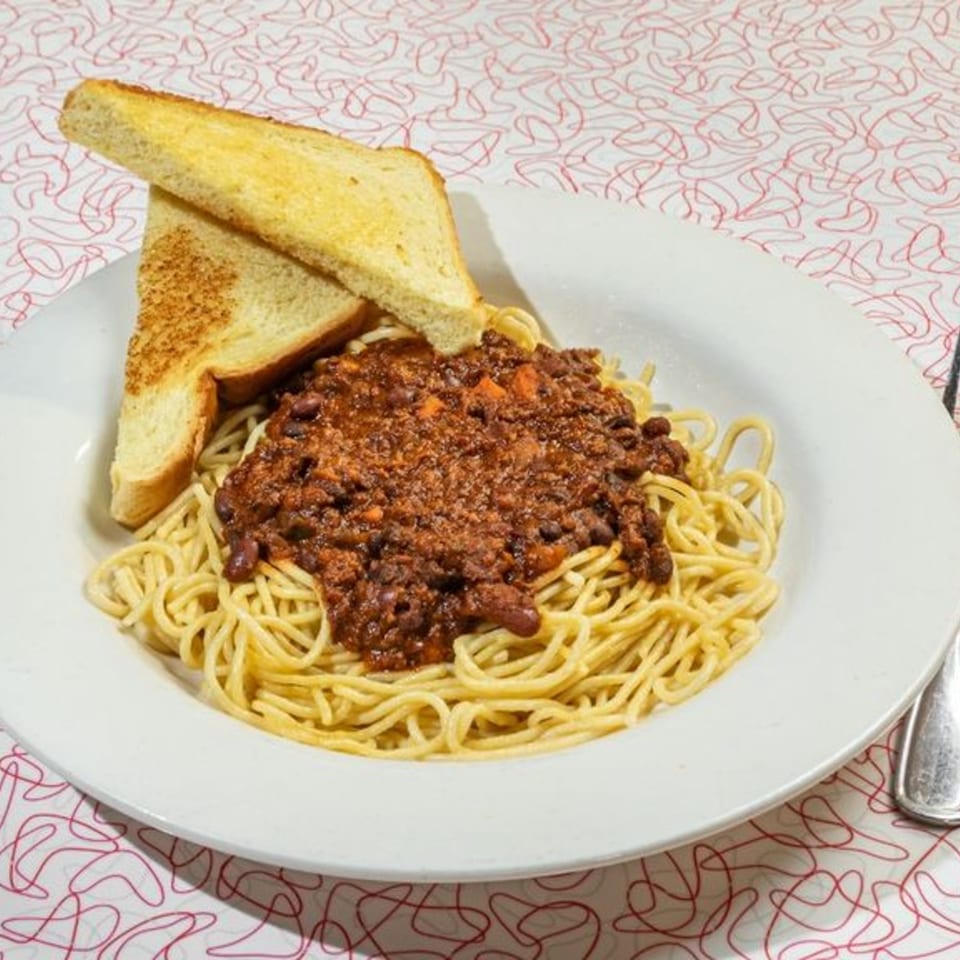 Big Boy's spaghetti with chili and two slices of buttered toast on a white plate.
