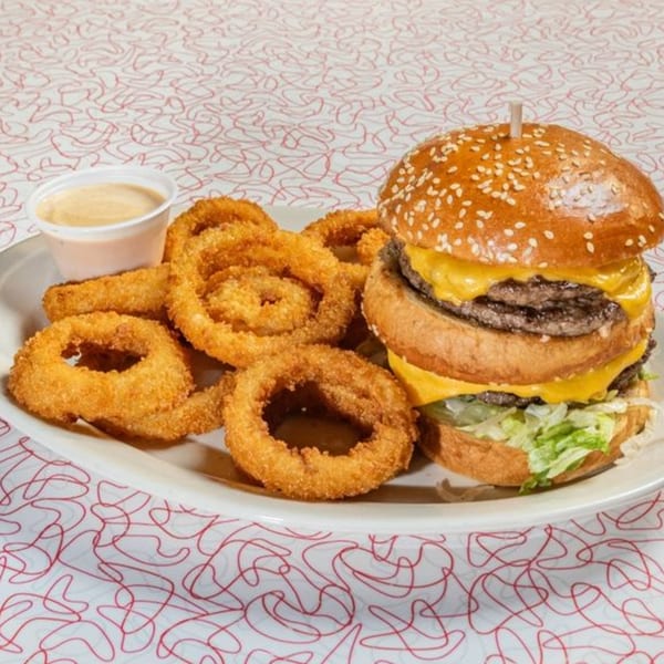Big Boy's double cheeseburger with lettuce, cheese, and sesame bun, served with onion rings and dipping sauce.